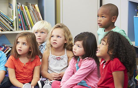 Elementary Pupils In Classroom Working With Teacher